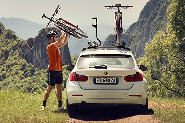 Cyclist mounting a bike to a car roof rack